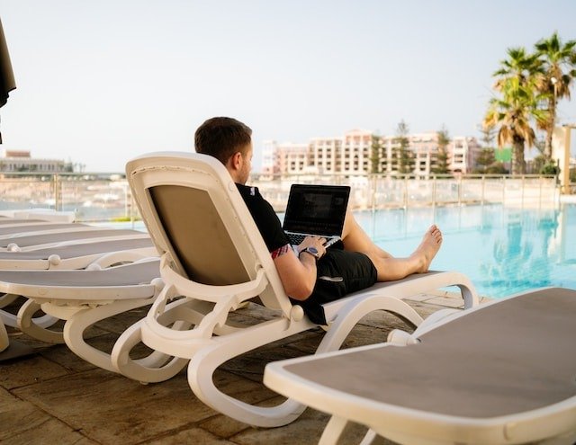 a guy using laptop in front of a pool